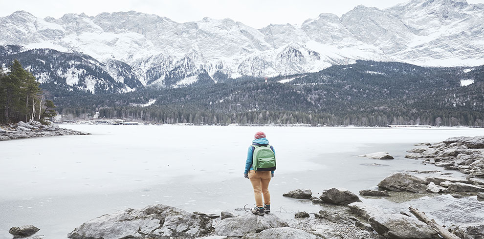 Young female hiker with backpack enjoying view to frozen lake Ei